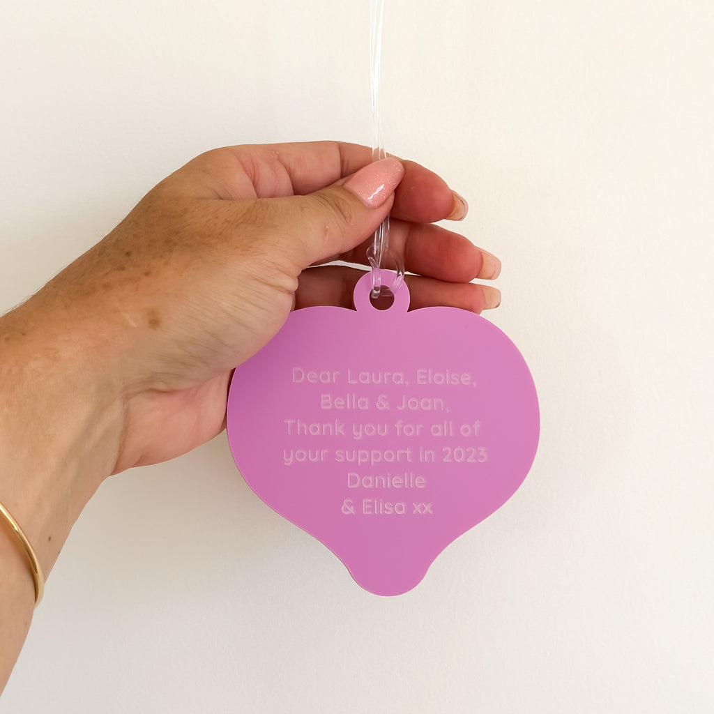 heart shaped pink and purple christmas decoration with personalised text engraved on the reverse