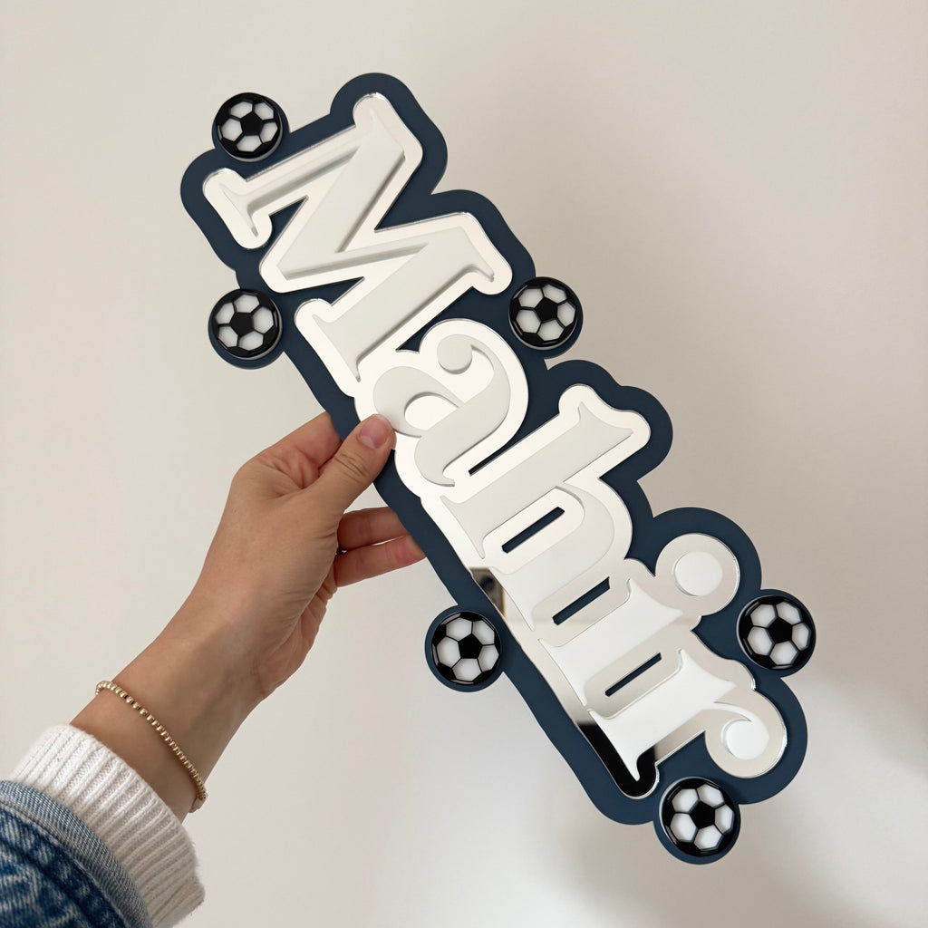 Hand holding decorative name sign with football details